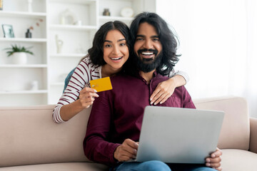 Happy indian lovers using laptop and credit card