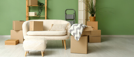 Sofa with cardboard boxes and pouf in living room on moving day