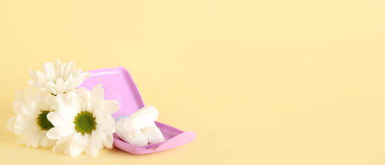 Storage box with tampons and chamomile flowers on beige background with space for text