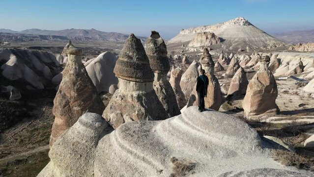 Aerial drone view of a person admiring the natural beauty of Pasabag Valley or Monks Valley and  Fairy Chimneys in Cappadocia, Turkey. Famous destination for hikers to explore the Rock Sites.