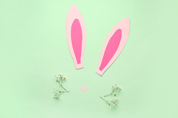 Paper bunny ears and gypsophila flowers on green background