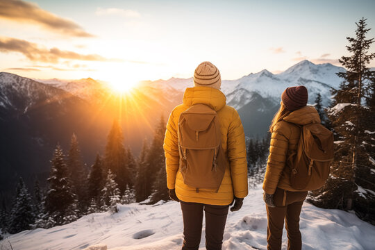 Generative AI back view image of an unrecognizable women in a yellow jacket standing together in winter outwear and backpack observing a sunset in a snowy mountain landscape