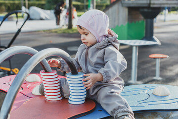 one small child 1 year and 3 months old plays on the playground in plastic multi-colored abacus