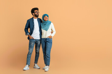 Stylish arab muslim couple in trendy clothes standing confidently and looking away