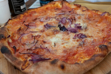 a pizza on a wooden board, served with cheese red onionand various toppings