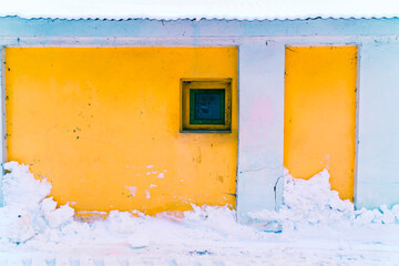 Yellow color wall with small window in winter