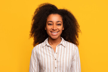 Happy african american lady smiling on yellow background