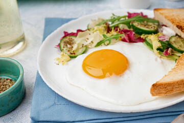 Plate with tasty fried egg, toast and salad on light table