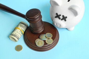 Piggy bank with judge gavel and money on blue background. Bankruptcy concept