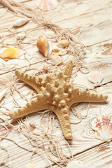 Beautiful starfish with seashells and net on light wooden background