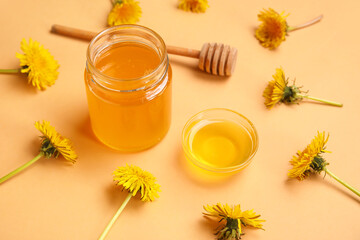 Jar and bowl with dandelion honey on orange background
