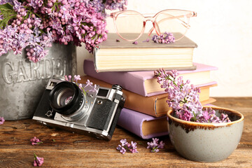 Composition with camera, notebooks and lilac twigs on wooden table