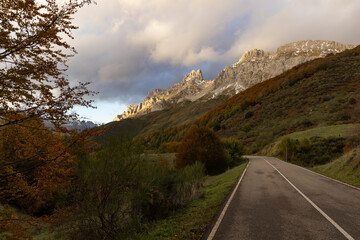 Landscape of Picos de Europa national park road through autumn forest with bright colorful leaves and sunset