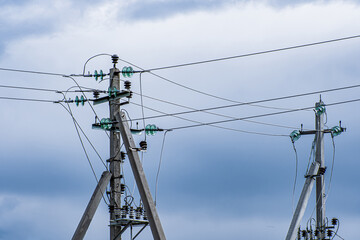 Power poles of high voltage line on cloudy sky background.