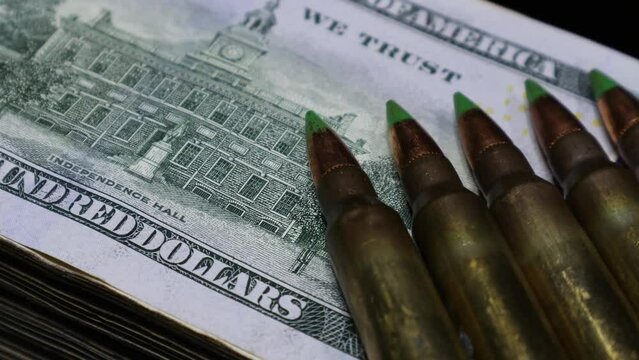 A macro level closeup of rifle bullets over The US dollar banknotes, a clip for the concept of the super power, global power, and The US hegemony over other countries and in The United Nations 