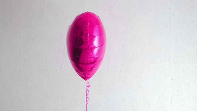 One beautiful big pink heart shaped balloon with ribbon isolated on a white background. Birthday party gift. Floating object. Inflatable ball by helium gas. Valentines day gift. Love symbol. 4k