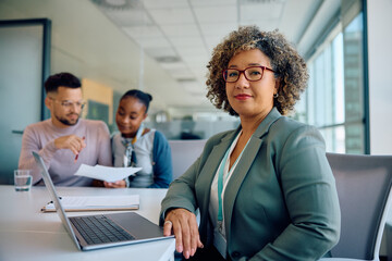 Smiling financial advisor during meeting with her clients looking at camera.