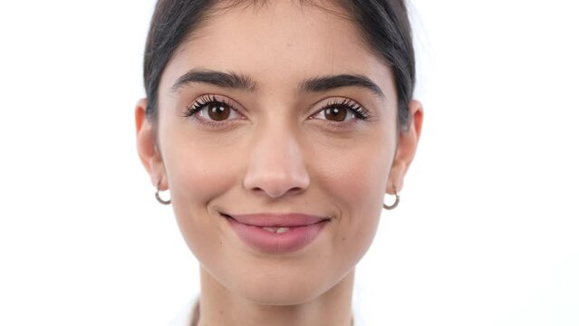 Young Caucasian woman captivates with direct gaze into the camera. The white background emphasizes presence, creating a visually compelling and focused image.