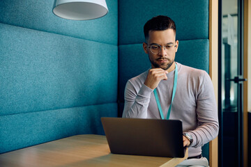 Young businessman working on laptop in office.
