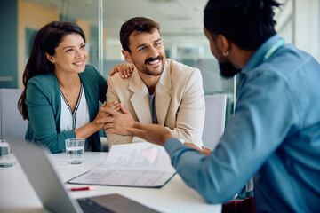 Happy couple talking to their financial advisor on meeting in office. - obrazy, fototapety, plakaty