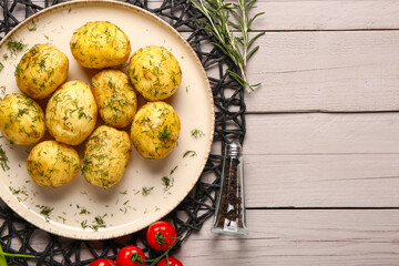 Plate of boiled baby potatoes with dill and tomatoes on grey wooden background