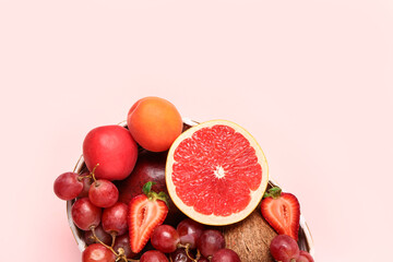 Wicker bowl with different fresh fruits on pink background