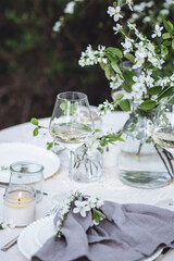 Romantic elegant luxury wedding table decor with white fresh spring blooming cherry apple tree flowers. Glass, candles, floral decoration for special marriage holiday event. No plastic zero waste