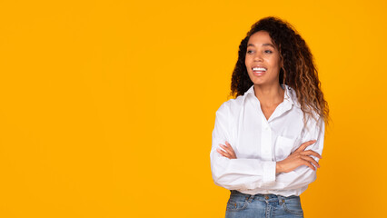 Black woman confidently posing with hands crossed against yellow background