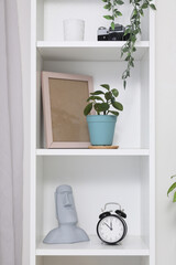 White bookshelf with houseplant, alarm clock and decor