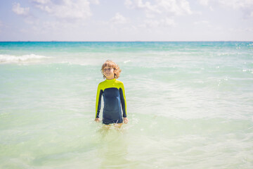 A carefree boy explores the wonders of the beach, with the sun-kissed shoreline as his playground, embodying the spirit of childhood adventure