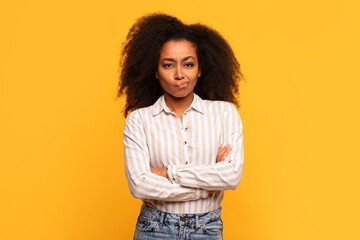 Skeptical black lady with arms crossed on yellow background - obrazy, fototapety, plakaty