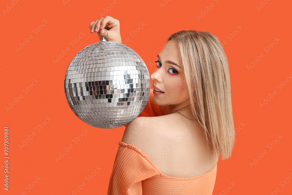 Wall mural beautiful young woman with disco ball on red background