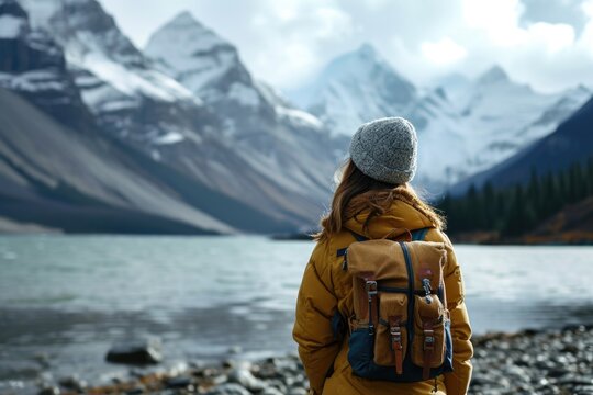 Scandinavian woman in a hat with a backpack on the background of nature and mountains looking at the lake.view from behind