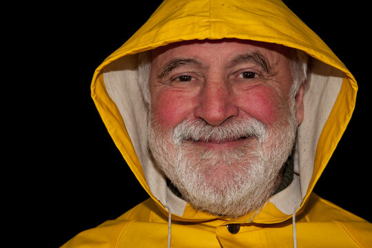 A retired sailor, smiling brightly and full of joy under his yellow hood, ready for the next adventure on dry land!