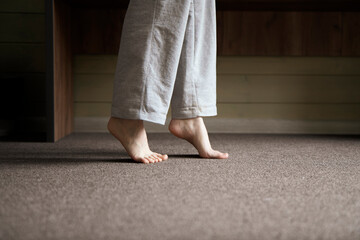 A close-up view shows bare feet standing on a carpeted floor, likely indicating the warmth from a...