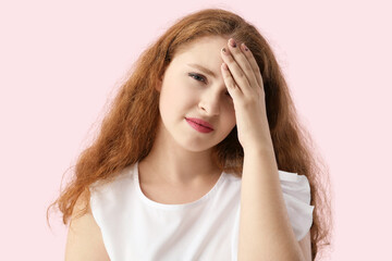 Portrait of pretty redhead woman suffering from headache on pink background