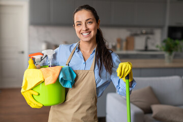 Confident cleaner with bucket and mop in a neat home