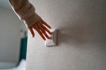 A hand effortlessly activates a light switch, instantly bringing brightness to a dark room.