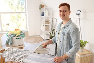 Handsome young man ironing clothes in laundry room