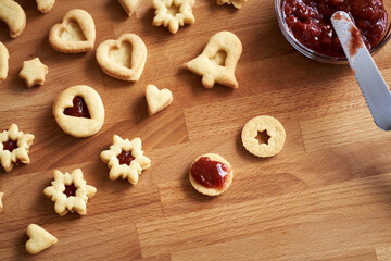 Filling homemade Linzer Christmas cookies with red strawberry marmalade