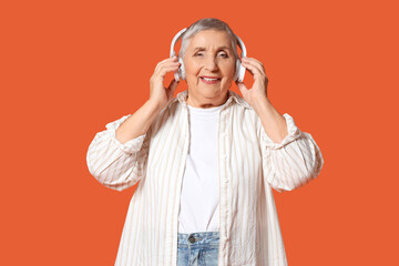 Senior woman in headphones on orange background