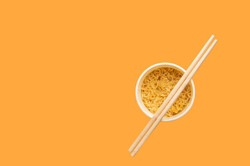 Overhead view of a bowl of instant pasta soup with a pair of chopstickson a yellow background. Lunch. Fast food concept