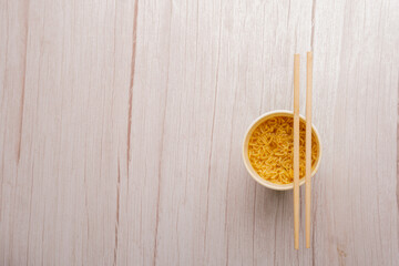 Overhead view of a bowl of instant pasta soup with a pair of chopstickson a with background. Lunch. Fast food concept