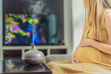 A blissful pregnant woman immerses in relaxation, savoring the soothing aroma from a diffuser while...