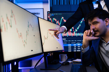 Stock traders pointing highest stock market on dynamic valued analysis on monitor real time screen,...