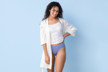 Young African-American woman in menstrual panties on blue background
