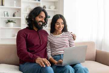 Cute young indian couple using computer at home