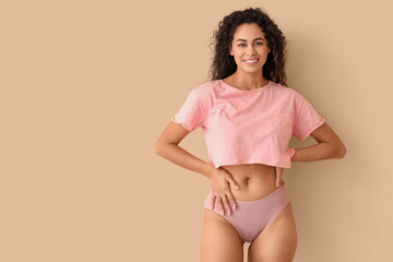 Young African-American woman in menstrual panties on beige background - obrazy, fototapety, plakaty