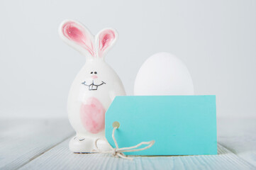 Happy Easter greeting card. Miniature wooden house. Rabbits, colorful eggs, spring flowers with tag for text