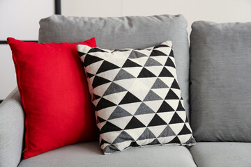 Cozy grey sofa with stylish cushions in living room, closeup